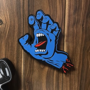 May include: A blue hand graphic with an open mouth and red tongue, with the text "43_FOREVER" above it. The hand has a black outline and is mounted on a wooden surface. The hand graphic is a popular design.