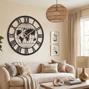 May include: A large circular wall clock featuring a black metal frame with Roman numerals and a central world map silhouette. The clock has two gold-colored hands positioned against the map, which is overlaid with thin black lines representing longitude and latitude.