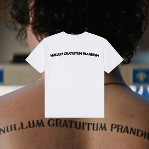 Peut inclure: Un t-shirt blanc à manches courtes avec le texte noir NULLUM GRATUITUM PRANDIUM imprimé dans une police grasse sans empattement sur le haut du dos. Le vêtement présente un col rond standard et une conception en tissu blanc uni.