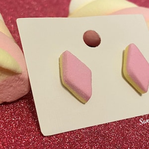 May include: A pair of pink and yellow diamond-shaped earrings on a white card with the text "Sweetstuff" in the bottom right corner.