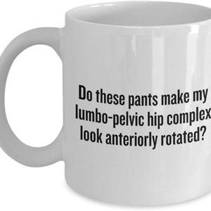 Puede incluir: Taza de cerámica blanca con asa curva. La taza presenta texto negro que dice: "¿Hacen estos pantalones que mi complejo de cadera lumbopélvica parezca rotado anteriormente?"
