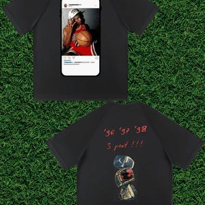 May include: Black t-shirt featuring a basketball player image in a social media frame on the front. The back of the shirt displays the text "'96 '97 '98 3 peat !!!" above a graphic of three championship rings.