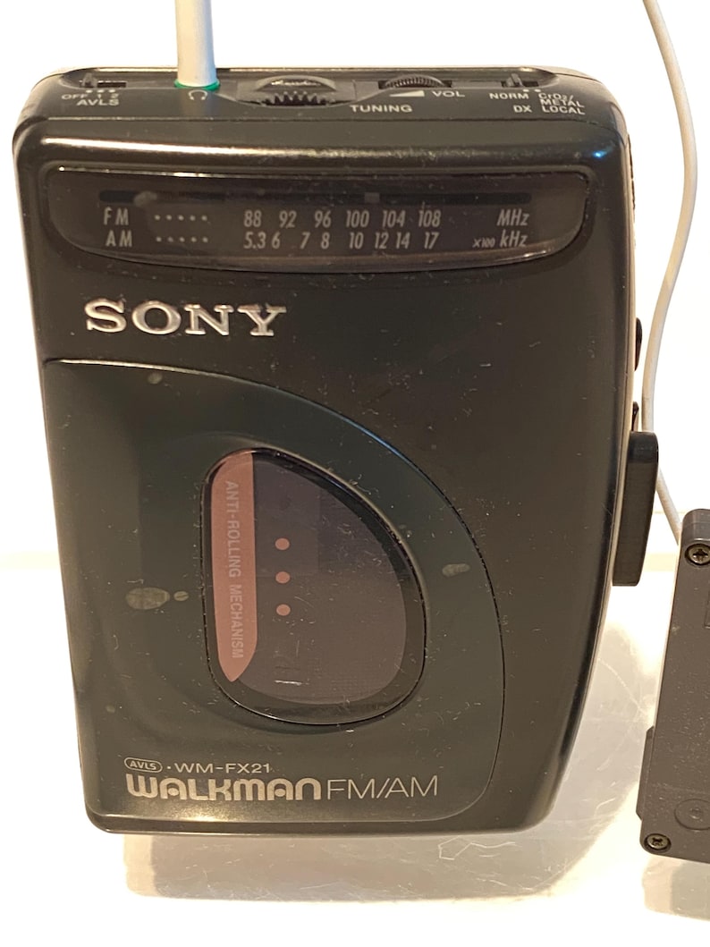 May include: Black Sony Walkman FM/AM radio with a tuning dial and frequency display. The radio has a headphone jack and the text "WALKMAN FM/AM" is visible. The radio is a vintage electronic device.
