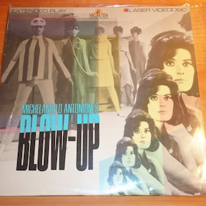 May include: A vintage laserdisc case for the film "Blow-Up" by Michelangelo Antonioni. The case features a colorful collage of images from the film, including a man in a striped suit and several women with long dark hair.