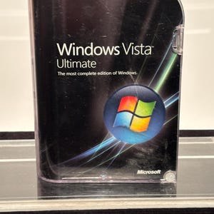 May include: A black Windows Vista Ultimate DVD-ROM software case with rounded top corners. The cover features the Windows logo, the text "Windows Vista Ultimate", "The most complete edition of Windows", and "32- and 64-bit" with the Microsoft logo.