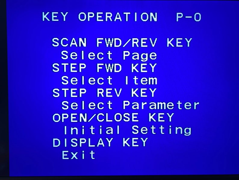 May include: A blue screen displays white text detailing key operations. The text includes commands like 'SCAN FWD/REV KEY', 'Select Page', 'STEP FWD KEY', and 'Exit'. The image is a close-up of the screen.