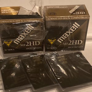 May include: Several boxes and individual units of Maxell MF2HD 3.5-inch high-density floppy disks. The boxes are black with gold and white text, including "Formatted IBM & Compatibles." The individual disks are also black.