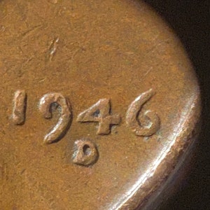 May include: Close-up of a copper-colored coin with the year 1946 stamped on it.