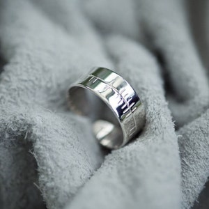 May include: A silver ring with a textured design on the band.