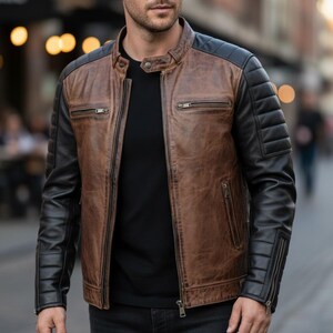 May include: A brown and black leather jacket with a stand-up collar and zipped pockets. The jacket has a quilted design on the black sleeves and shoulders. The jacket is worn over a black top.