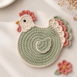May include: A handmade crochet chicken-shaped trivet in shades of green, cream, pink, and yellow. The trivet features a spiral design and a decorative flower. This item is perfect for kitchen decor.