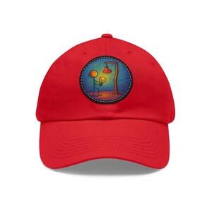 Pode incluir: Boné de beisebol vermelho com um patch circular com uma ilustração colorida. A ilustração mostra uma figura de palito segurando uma lâmpada perto de um poste de luz. O patch é delineado com uma linha branca tracejada.