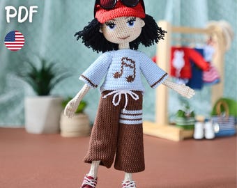 May include: A crocheted doll wearing a red cap with sunglasses, a light blue shirt with a musical note, and brown pants. The doll has black hair and red and white sneakers. The image includes the text "PATTERN PDF" and an American flag.