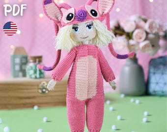 May include: A handmade crochet doll in a pink Angel costume. The doll has a light pink body, a darker pink costume, and a matching hat with large ears. The doll has blonde hair, blue eyes, and is holding a crochet pattern. The text "PATTERN PDF" is visible.