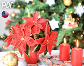 May include: A vibrant arrangement of red crocheted poinsettias in a red vase, with green leaves and gold accents. Two red candles are lit, and a gold and silver ornament are on the table. The image includes the text "PATTERN PDF".