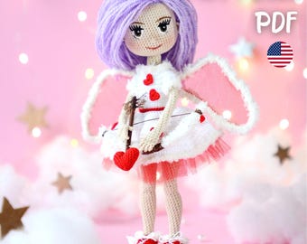 May include: A handmade crochet doll in the shape of Cupid, with purple hair, white dress with red hearts, pink wings, and red shoes. The doll holds a bow and a red heart. The image includes the text "PATTERN PDF" and the American flag.