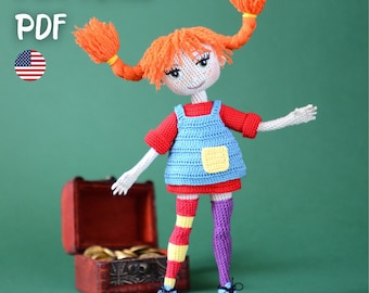 May include: A crochet doll with bright orange yarn hair in two pigtails, wearing a red shirt, blue overalls with a yellow pocket, and mismatched striped stockings in red, yellow, and purple. The doll wears light blue shoes and stands near a small brown treasure chest. Text reads PATTERN PDF.