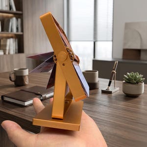 Premium gold aluminum flipping photo stand. Close-up details of a high-quality metal rotating desk calendar and picture frame. Luxury office decor.