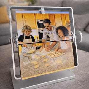 Rotating metal  silver colour picture frame displaying a family baking photo. Freestanding double-sided desk photo display, personalized gift for dad and family keepsake.