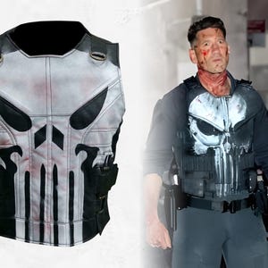 Op de afbeelding: Een wit en zwart tactisch vest met een schedelontwerp op de voorkant. Het vest heeft zwarte accenten, riemen en zakken. Het schedelontwerp is prominent aanwezig, met rode accenten. Het vest is ontworpen om over kleding te worden gedragen.