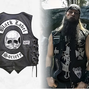 Puede incluir: Chaleco de cuero negro con un parche de calavera y las palabras "Black Label Society" y "Society" en letras blancas. El chaleco tiene cordones laterales y un cierre de botón. La imagen también muestra a una persona usando un chaleco similar.