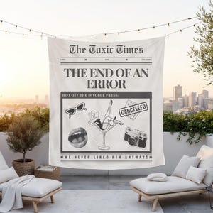 May include: A white tapestry with a newspaper-style design. The headline reads "The Toxic Times" and "THE END OF AN ERROR." Below, a graphic includes sunglasses, lips, a woman in a martini glass, a camera, and a "CANCELLED" stamp. The text "WE NEVER LIKED HIM ANYWAYS" is also present.
