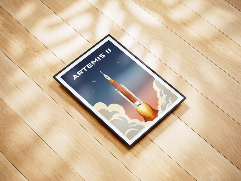May include: Framed art print featuring a rocket launching into space, with the text "ARTEMIS II" at the top. The artwork has a retro style, with a color palette of orange, blue, and white. The print is in a black frame.