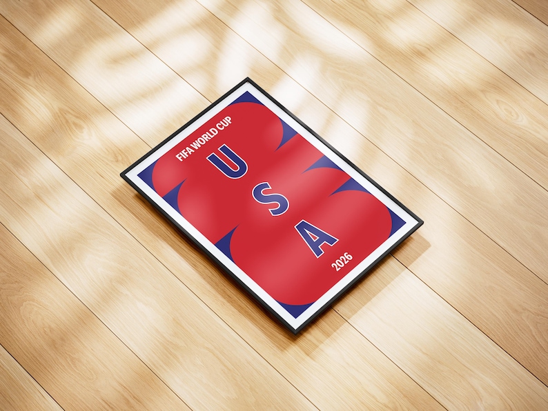 May include: A rectangular framed poster featuring a dark blue background with large, overlapping red circular shapes. The text FIFA WORLD CUP is printed in white at the top, with the letters USA stacked vertically in blue and the year 2026 in white.