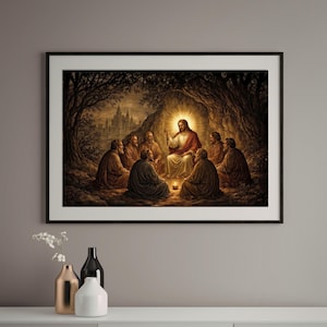 Puede incluir: Obra de arte enmarcada que representa una escena religiosa. Una figura central con túnicas rojas y blancas está iluminada, rodeada de figuras sentadas. La obra está ambientada en un entorno similar a una cueva con una ciudad al fondo, todo dentro de un marco negro.