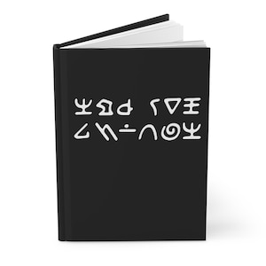 Peut inclure: Un journal noir avec du texte blanc dans une langue inconnue. Le journal est ouvert, révélant des pages blanches. La couverture présente une série de symboles. Le journal est de style couverture rigide.