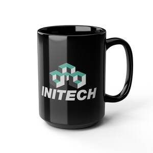 May include: A black ceramic mug featuring the word "INITECH" in white, and a teal and white geometric design. The mug has a large handle, suitable for hot drinks.