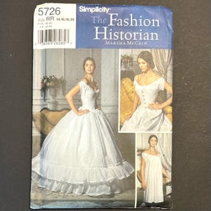 May include: A Simplicity 5726 sewing pattern envelope titled The Fashion Historian by Martha McCain. The package displays three white garment variations including a full-skirted gown with ruffles, a fitted bodice with buttons, and a simple shift dress.