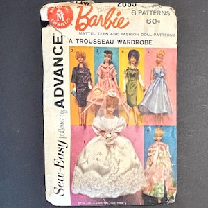 May include: Vintage Barbie doll sewing pattern titled "A Trousseau Wardrobe" featuring six different fashion designs. The pattern cover shows illustrations of Barbie dolls in various outfits, including a wedding dress and other dresses.