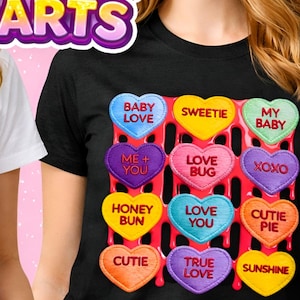 May include: Two t-shirts, one white and one black, each featuring a colorful design of conversation heart candies. The hearts have phrases like "Baby Love" and "Sweetie". The image also has the text "CUTE HEARTS".
