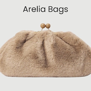 Puede incluir: Texto Arelia Bags sobre un clutch beige y esponjoso con cierre de beso. El bolso tiene un aspecto suave y texturizado, y el cierre presenta dos pequeñas cuentas redondas y claras.