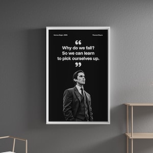 May include: A framed black and white print featuring a quote from Thomas Wayne: "Why do we fall? So we can learn to pick ourselves up." The print includes the text "Batman Begins - 2005" and a portrait of a man in a suit.