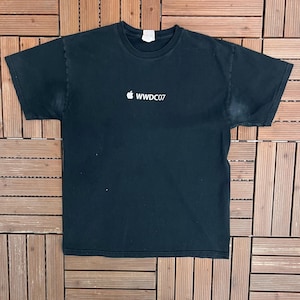May include: Black t-shirt with a white Apple logo and the text "WWDC07" printed on the front. The shirt is made of a soft material and has a crew neck.