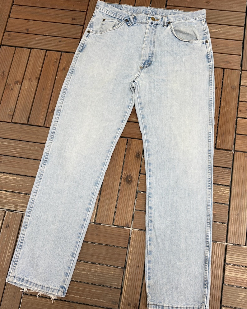 May include: Light blue denim jeans with a classic five-pocket design. The jeans have a straight leg cut and a faded wash, giving them a vintage look. The jeans are made of durable denim material.