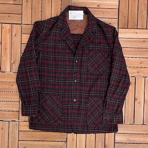 May include: A burgundy and black plaid jacket with two front pockets and a chest pocket. The jacket has a button-up front and a collar. The fabric has a green accent in the plaid pattern. A tag is attached to the collar.