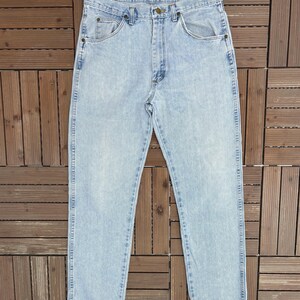 May include: Light blue denim jeans with a classic five-pocket design. The jeans have a straight leg cut and a faded wash, giving them a vintage look. The jeans are made of a durable denim material.