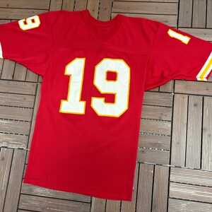 May include: A red football jersey with the number 19 in large white block letters outlined in yellow on the front. The number 1 is visible on the left sleeve and the number 9 on the right sleeve. The sleeves have yellow and white stripes.