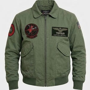 May include: An olive green bomber jacket with a full-length front zipper, a fold-down collar, and ribbed cuffs and hem. The jacket features multiple embroidered patches, including a Top Gun logo with the text Capt Pete Mitchell and a US flag.