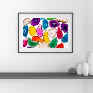 Könnte beinhalten: Ein gerahmter Druck mit einer Sammlung farbenfroher Achatscheiben. Die Scheiben haben verschiedene Formen und Größen und weisen eine Reihe von Farben auf, darunter Lila, Blau, Grün, Gelb und Rot. Die Achatscheiben sind vor einem weißen Hintergrund angeordnet.