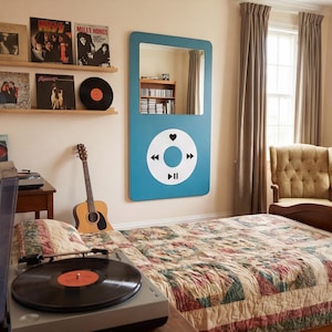 Può includere: Una camera da letto con uno specchio blu a forma di lettore musicale, un letto con una trapunta fantasia, una chitarra e un giradischi. I dischi in vinile sono esposti su mensole sopra il giradischi.