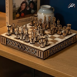 Op de afbeelding: Een houten schaakspel met ingewikkeld ontworpen stukken. Het schaakbord is lichtbruin met donkerbruine vierkanten en een decoratieve rand. De schaakstukken zijn lichtbruin met een contrasterend ontwerp. De set wordt gepresenteerd op een houten oppervlak.