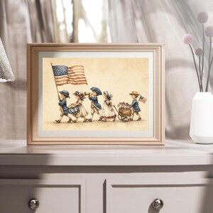 Op de afbeelding: Een ingelijste print met een aquarelillustratie van vijf kinderen in historische kleding die in een parade marcheren. De kinderen dragen een Amerikaanse vlag, spelen op een trommel en hoorn, en trekken een houten kar vol kleine vlaggetjes op een beige achtergrond.