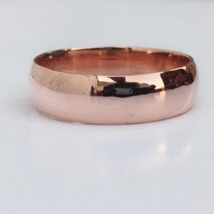 Op de afbeelding: Een roségouden ring met een glad, gepolijst oppervlak. De ring heeft een afgeronde band en reflecteert licht, waardoor een glanzende uitstraling ontstaat. Dit sieraad is een klassiek ontwerp, geschikt voor diverse gelegenheden.