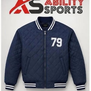 May include: A navy blue quilted bomber jacket featuring a full-length front zipper, a ribbed collar, and ribbed cuffs with white stripes. The number 79 is embroidered in white on the left chest. The text AS ABILITY SPORTS appears above.