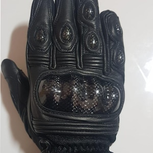 Könnte beinhalten: Ein schwarzer Motorradhandschuh aus Leder mit Knöchelschutz aus Carbon, verstärkten Fingerschützern und Netzeinsätzen. Das Logo AS ABILITY SPORTS ist oben in Rot und Schwarz aufgedruckt. Der Handschuh verfügt über Steppnähte und ein Handgelenkband.