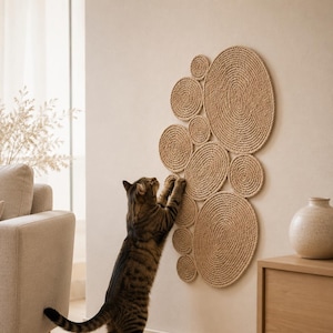 Handmade wall-mounted cat scratcher mat made from natural jute rope, shown in a neutral home interior with a cat using the vertical scratching surface.